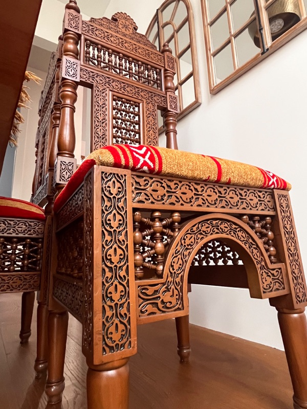 A chair back in detail, its upper panel filled with rows of hand-turned spindles.