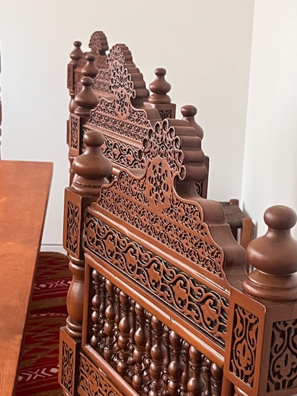 A chair seen from the side, the carved side panel and turned legs visible.