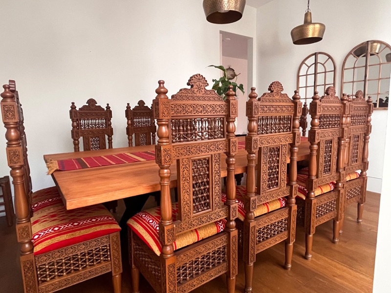 The complete set of twelve chairs around the table, each chair back carved with arabesque relief and turned spindles.